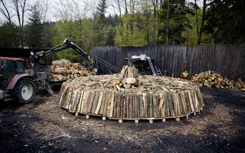 Holz für den Kohlenmeiler wird geschlichtet.