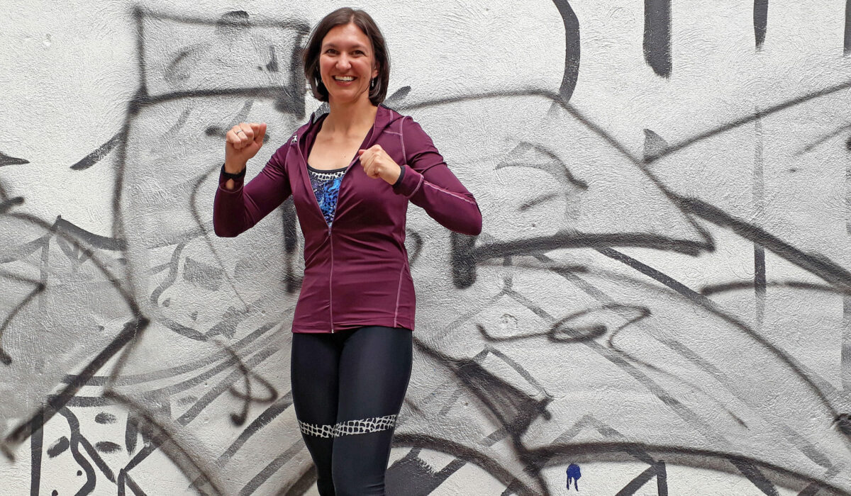 Mag. Sophie Wirth im Sportoutfit vor einer Graffiti Mauer